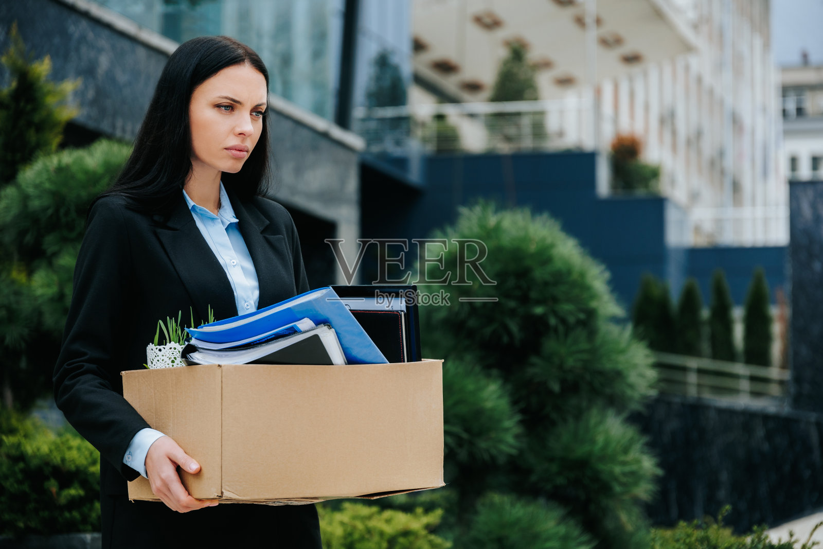 一个没有工作的现实女人站在外面，手里拿着一箱东西照片摄影图片