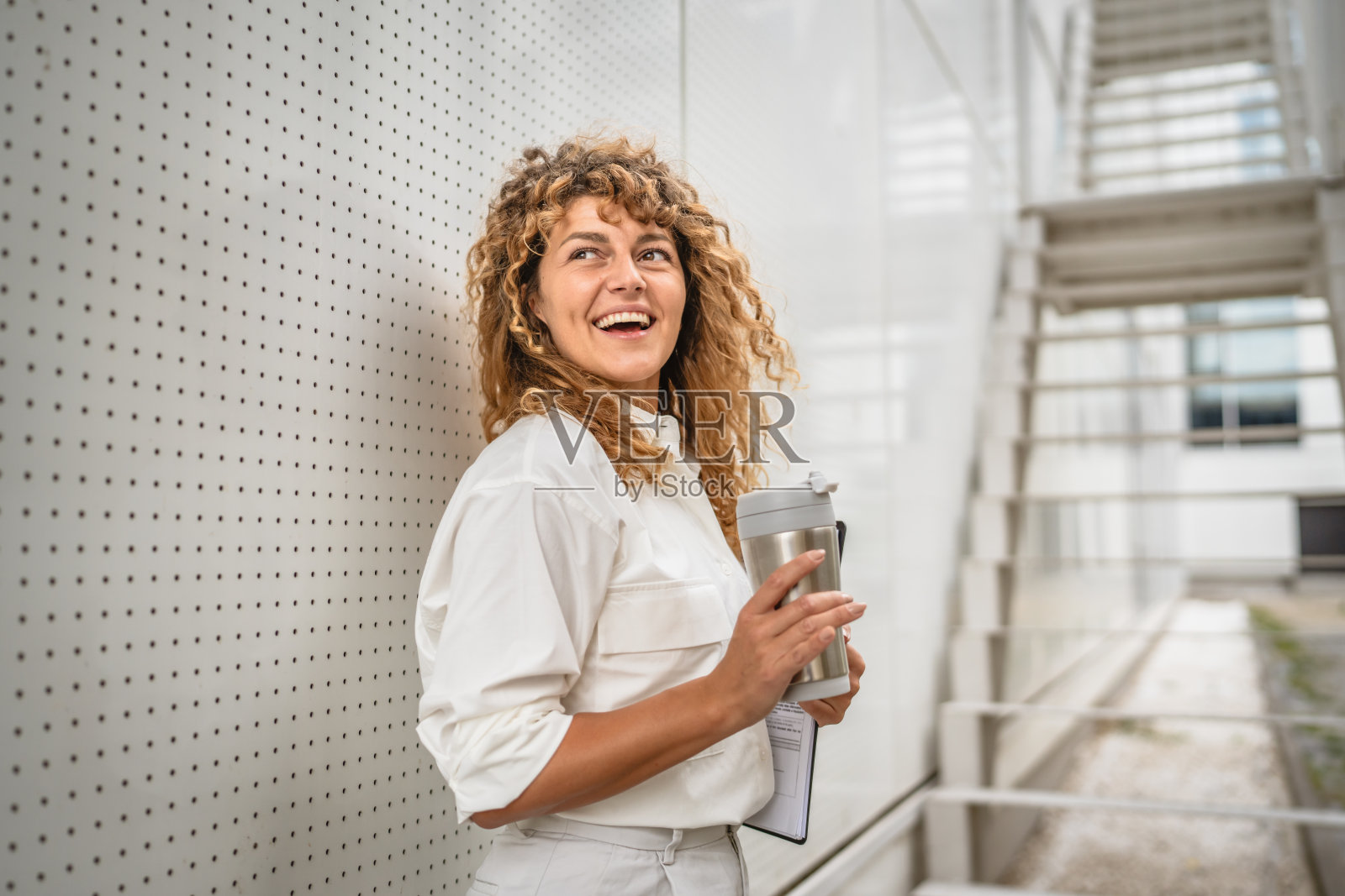 成年女商人站着拿着写字板和保温杯照片摄影图片