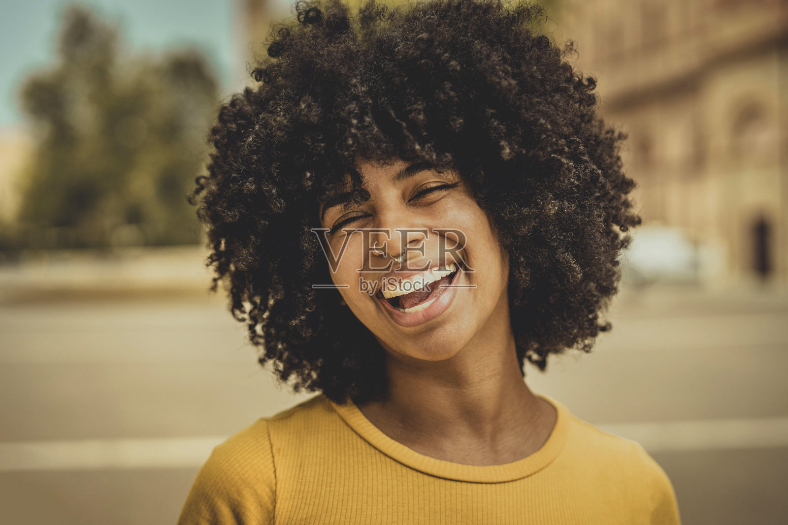 在户外对着相机微笑的非洲妇女-在户外大笑的卷发非洲妇女的肖像照片-快乐的人们生活方式的概念照片摄影图片