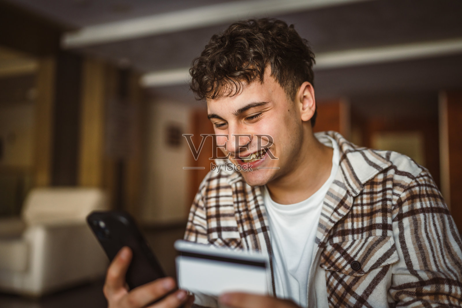 小男孩站着用信用卡在手机上网购照片摄影图片