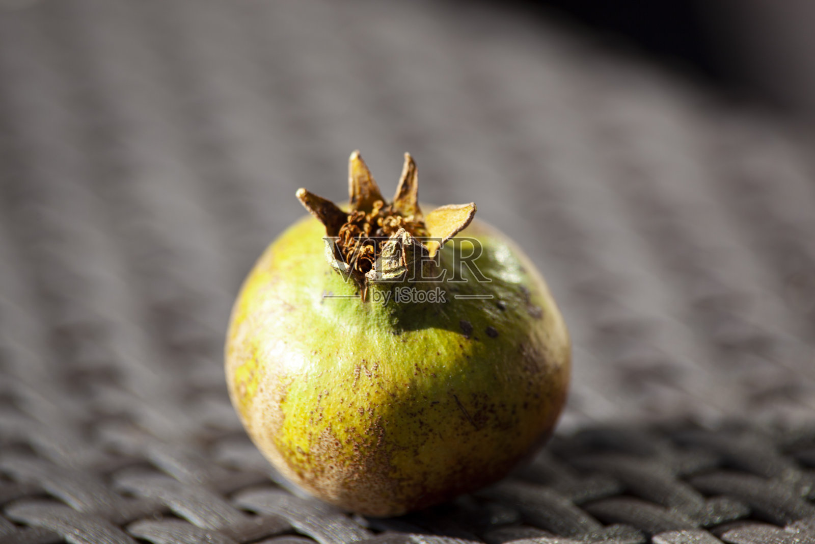 柳条桌上的绿石榴。秋天的果实。水平照片摄影图片