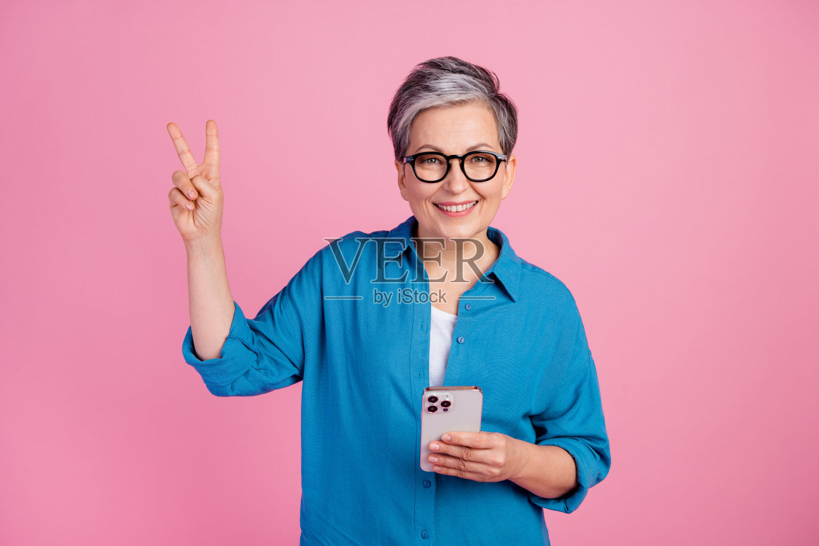有吸引力的高级妇女的照片肖像显示v字穿着时尚的蓝色衣服孤立的粉红色背景照片摄影图片