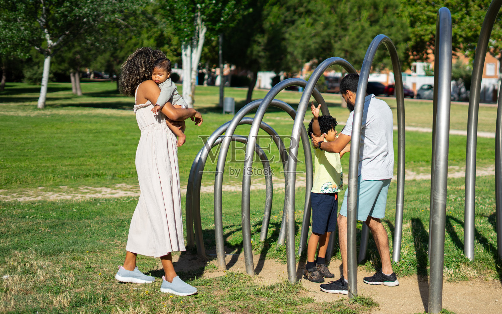 一个拉丁家庭，有一个婴儿和一个8岁的男孩在一个阳光明媚的日子里在户外公园玩耍照片摄影图片