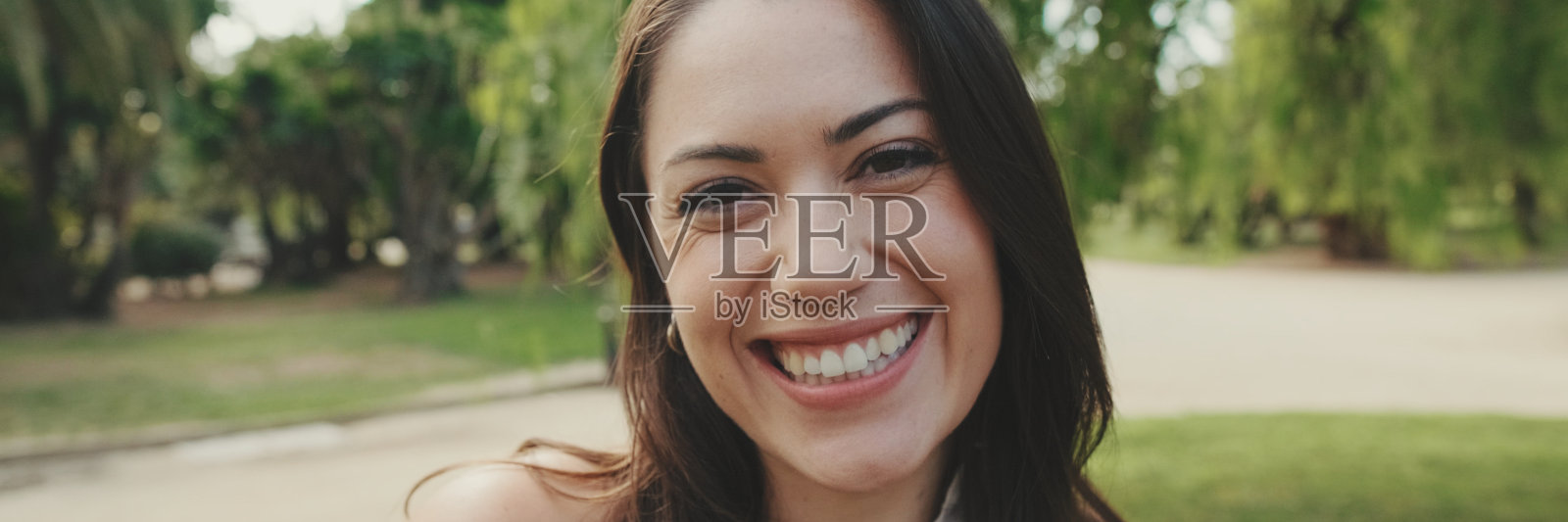 特写，年轻女子在公园里看着镜头微笑，全景照片摄影图片