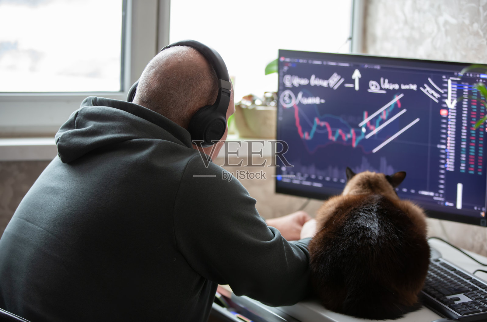 一名男交易员坐在家里的电脑前，监视股票交易所的时间表，从事交易和股票交易。照片摄影图片