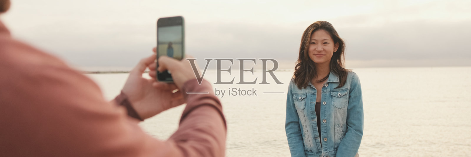 男人在岸边给女人拍照，全景照片摄影图片