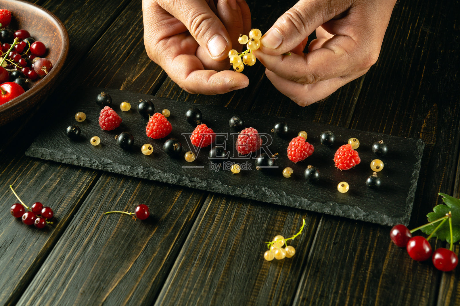 一名厨师在吃之前把成熟的不同浆果放在黑色的分拣板上。黑板上的广告位照片摄影图片