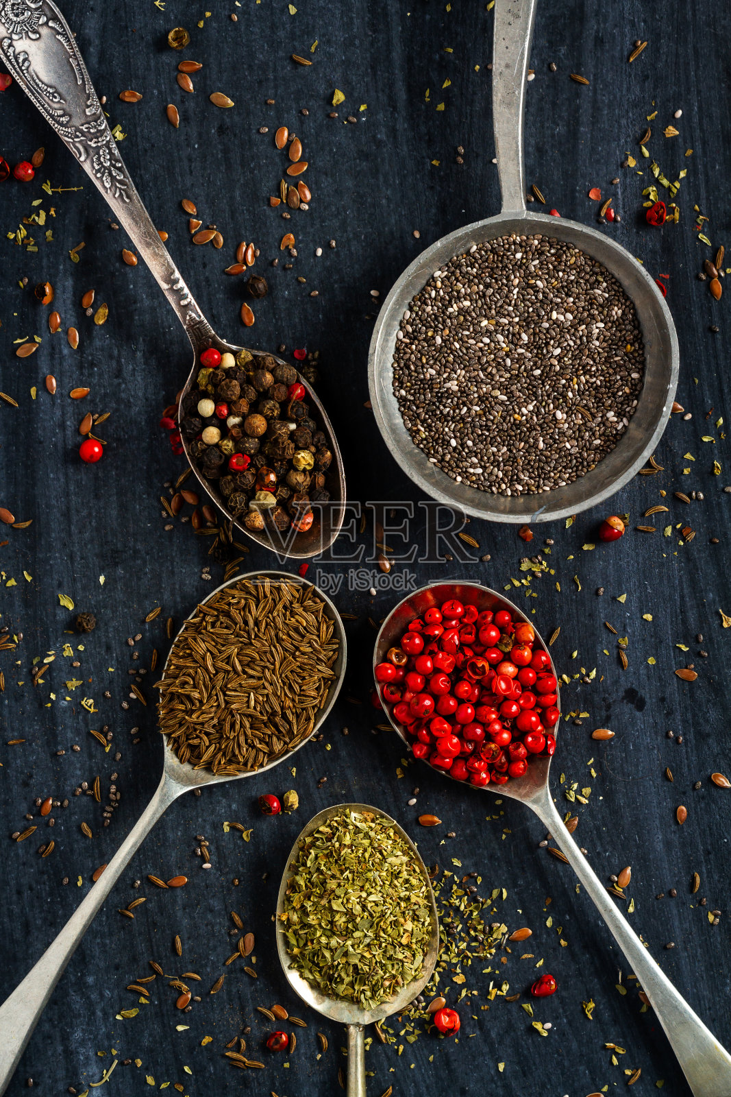 黑色背景上放着各种种子和香料的旧勺子照片摄影图片