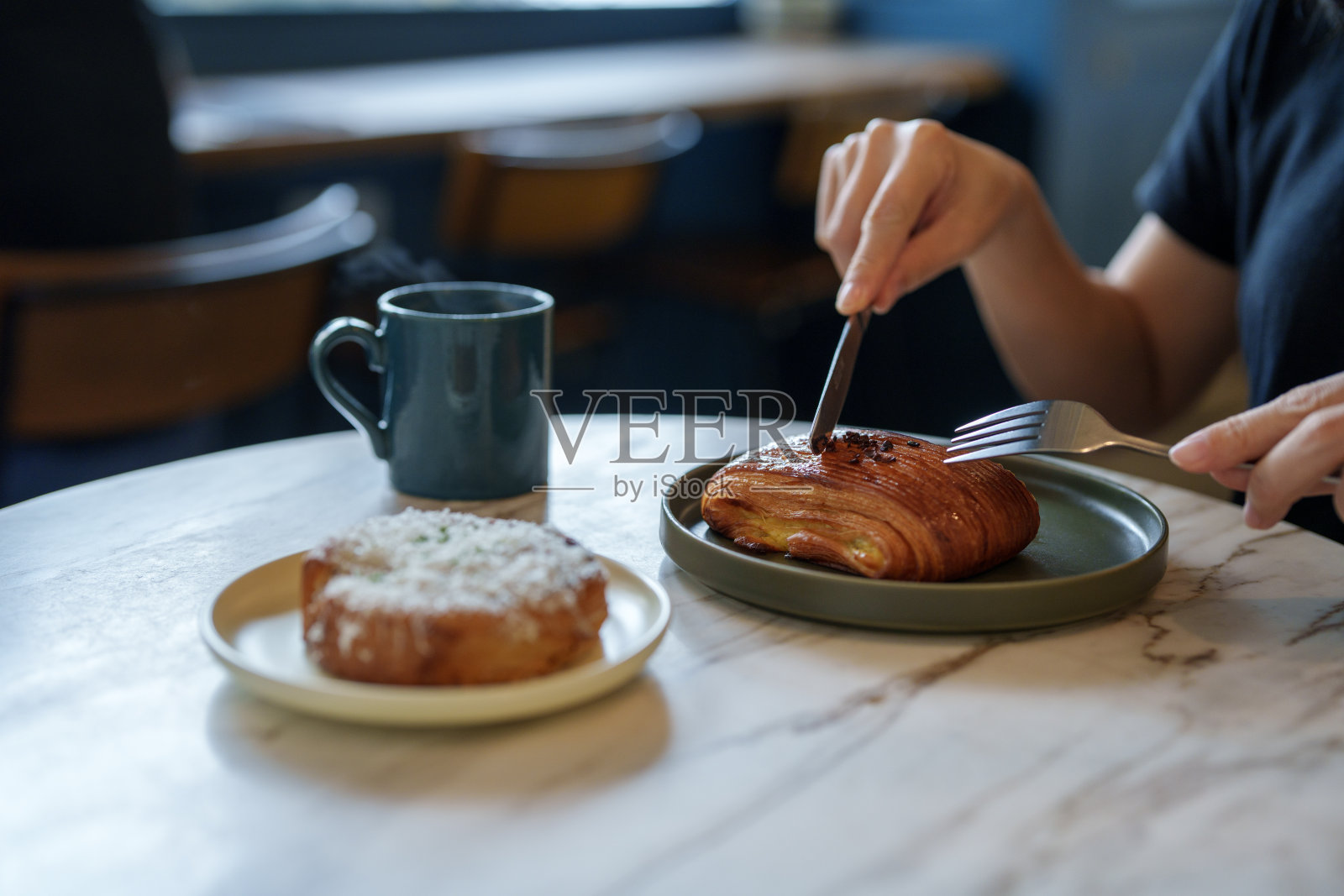 一个年轻的女人享受她的早餐，法国糕点和一杯热咖啡的早晨在咖啡馆照片摄影图片