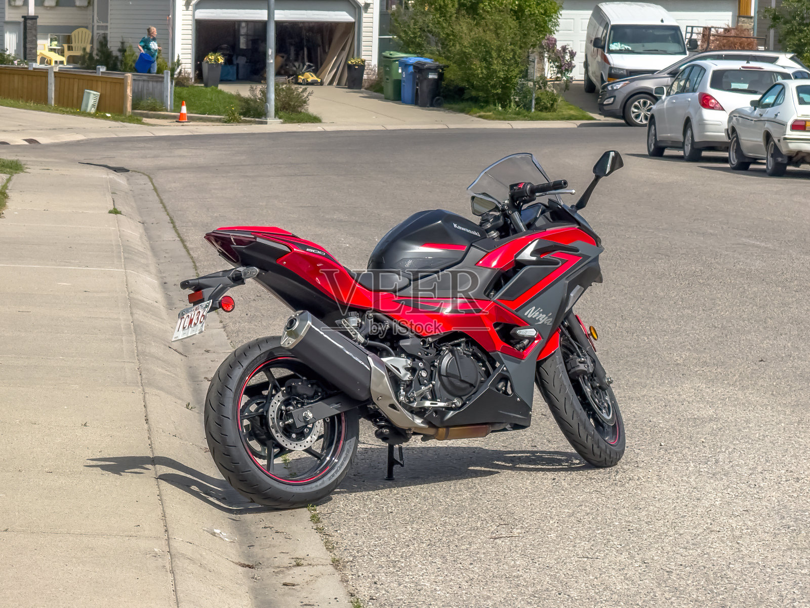 一辆红色的川崎忍者摩托车停在路边，背景是一所房子。在摩托车的侧面可以看到Ninja的文字。照片摄影图片