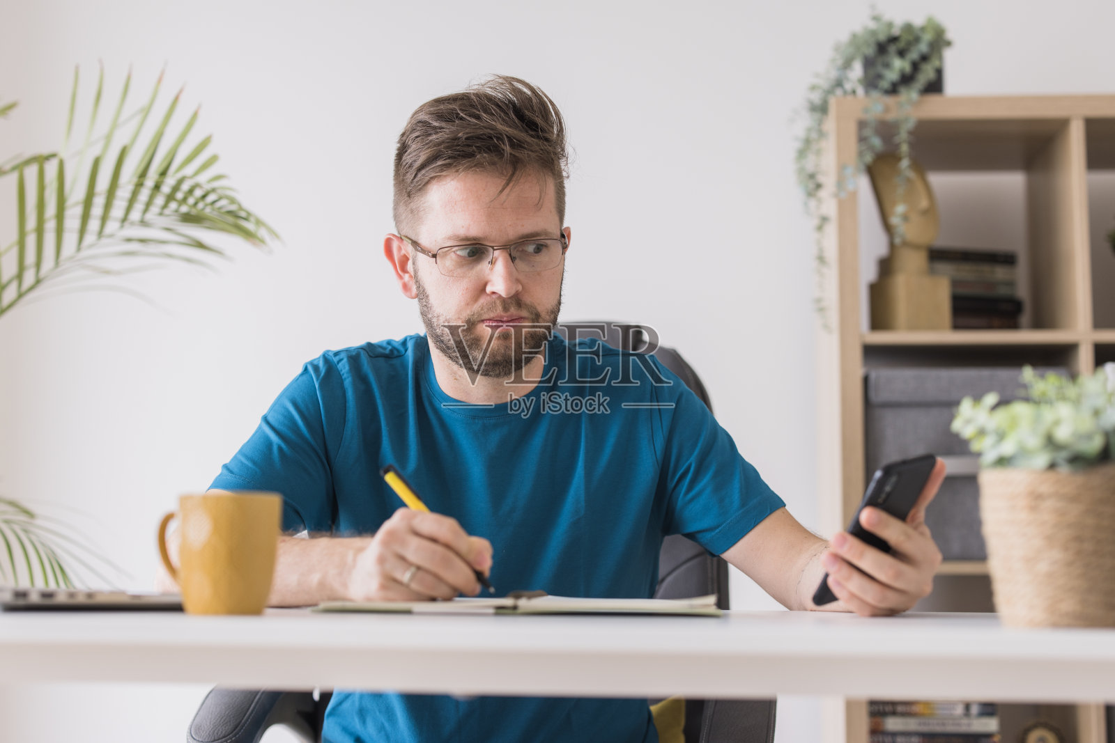 严肃的商人使用智能手机和做笔记照片摄影图片