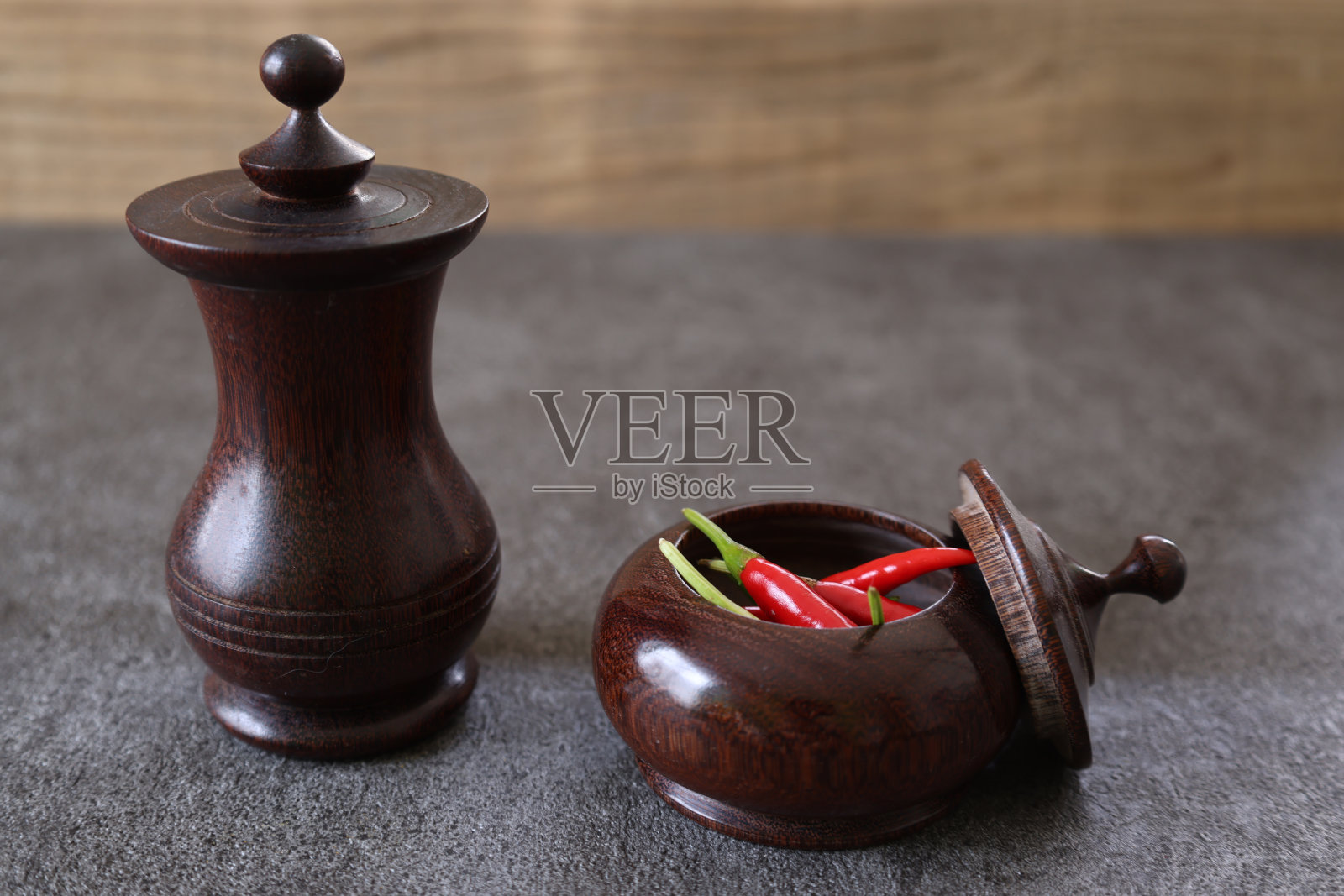红辣椒装在木餐具里，放在石纹桌上。照片摄影图片