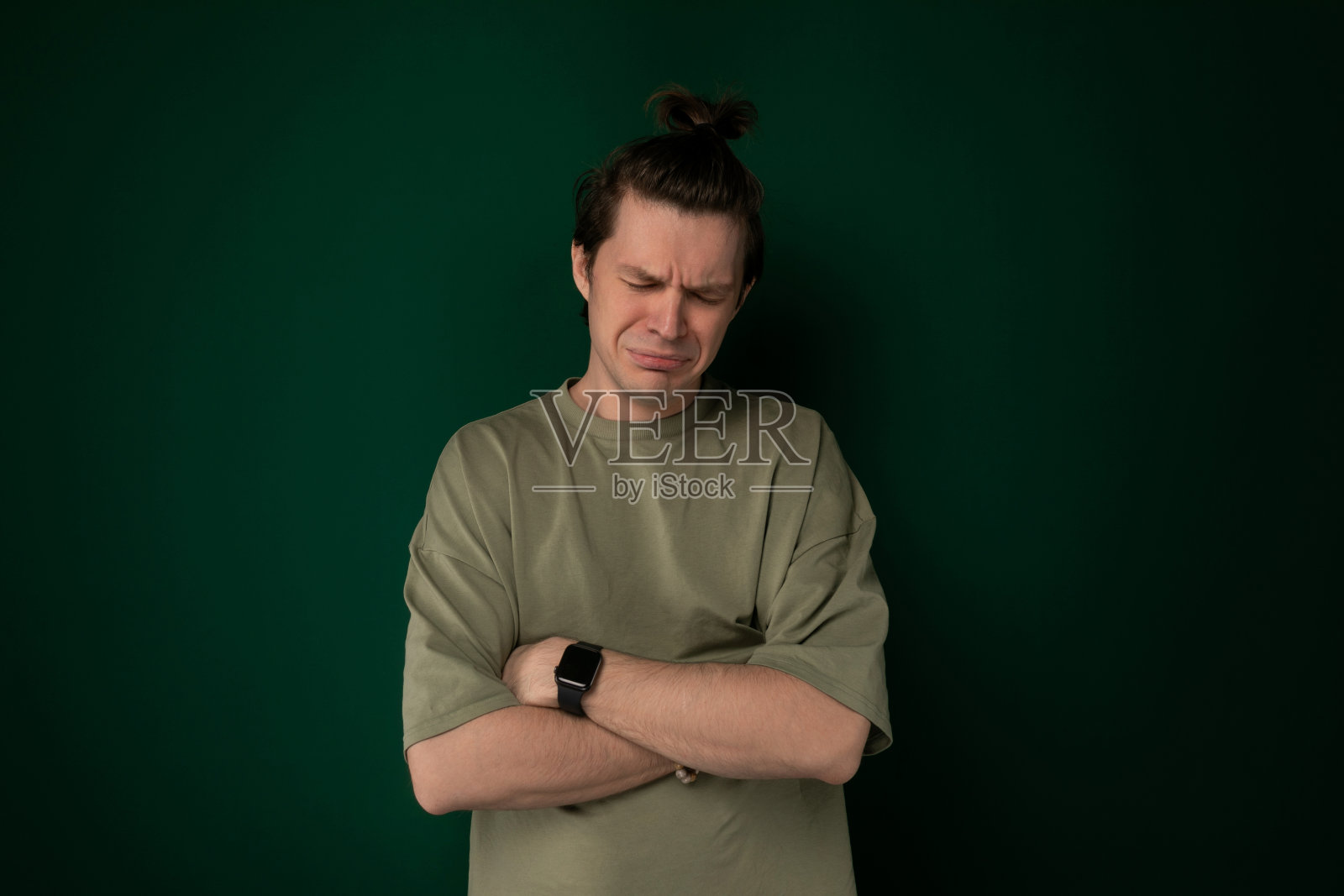 男子双手交叉站在绿墙前照片摄影图片