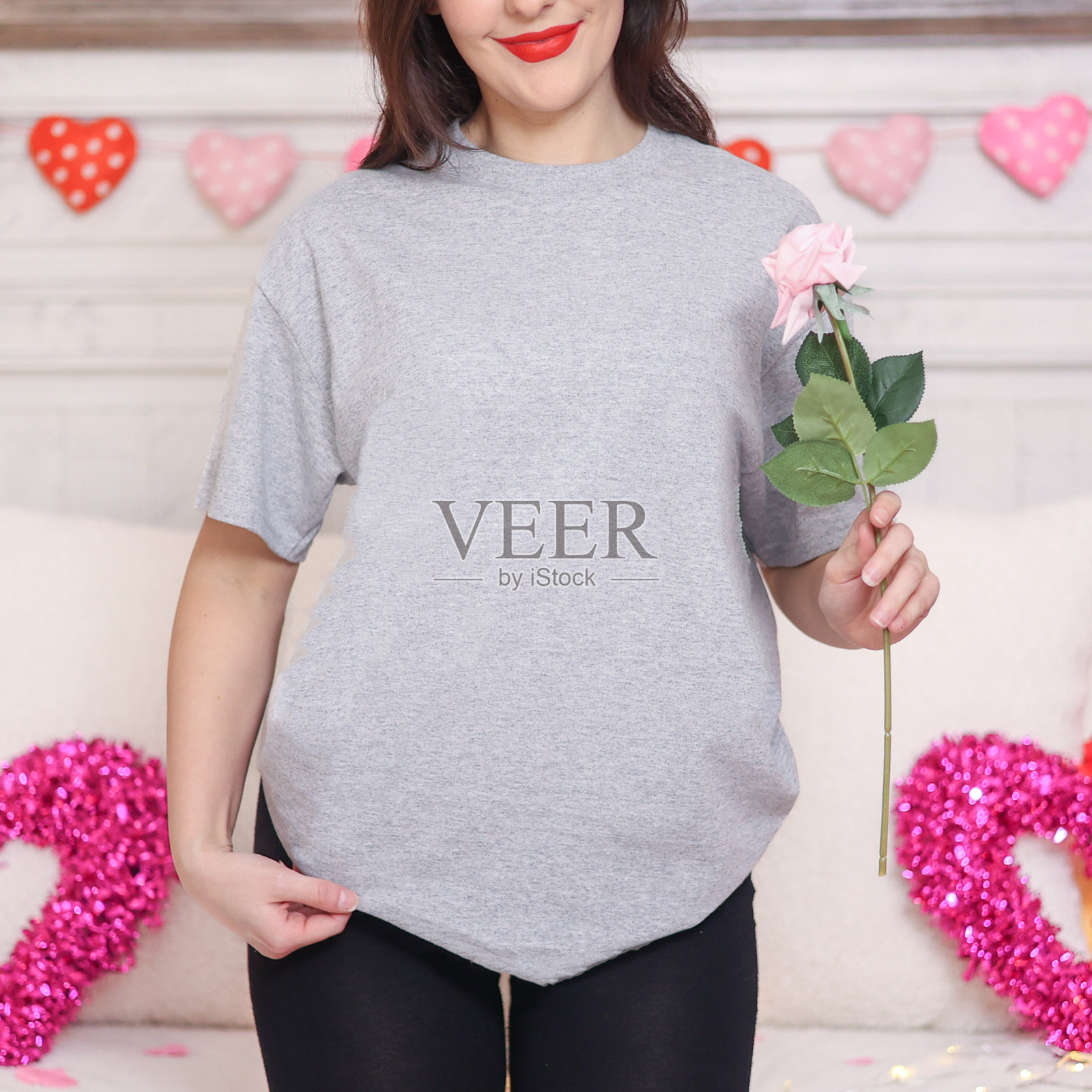 年轻的黑发模特在床上装饰情人节浪漫的假期。穿着素色上衣。心照片摄影图片