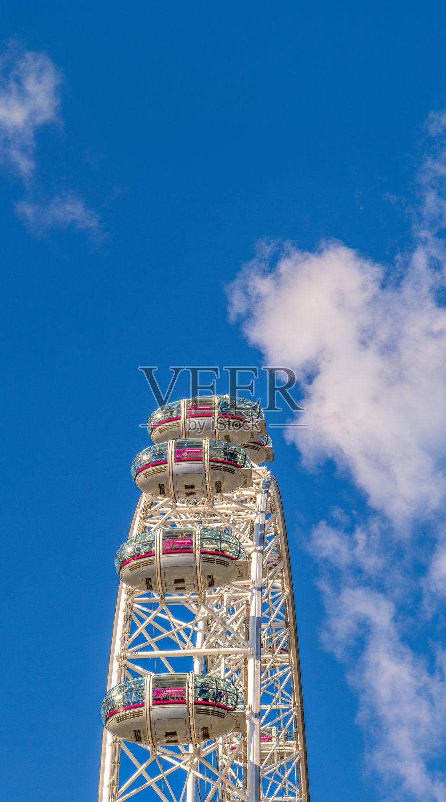 从世界上最大、最高的摩天轮“伦敦眼”或“千禧眼”的下方侧视图，游客们坐在贡多拉上，在蓝天下拍照。照片摄影图片