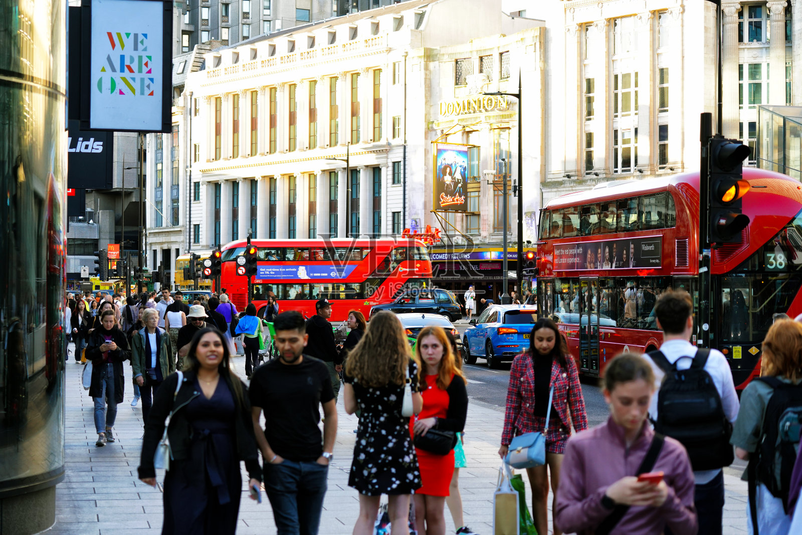 英国伦敦市中心牛津街附近的查令十字路口上,人们走在展示音乐剧《姐妹行动》的道明剧院建筑立面上照片摄影图片