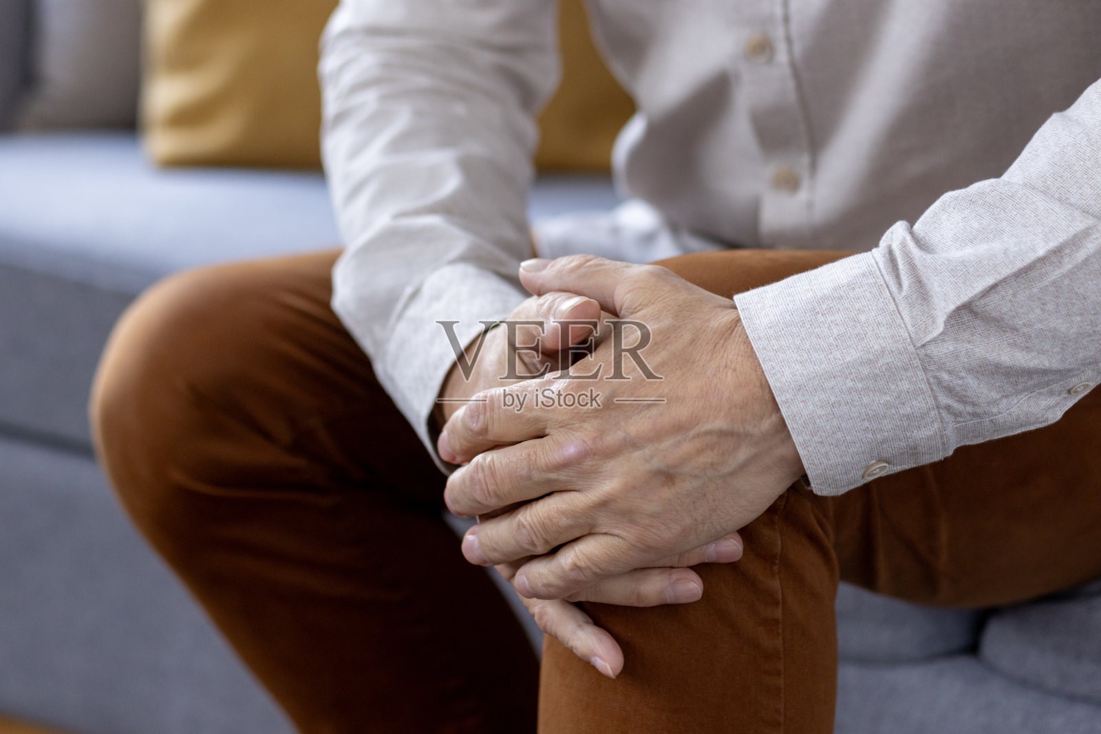 身体部分照片，老人的手握着棕色裤子的腿膝盖，感到剧烈的疼痛和扭伤照片摄影图片