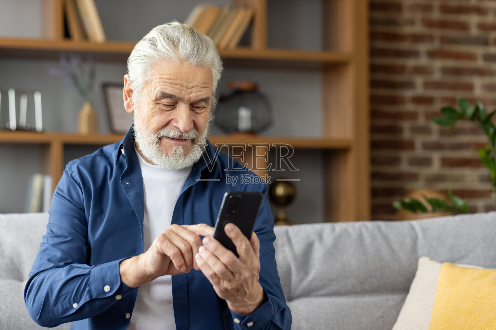 一位老人在家里用智能手机发短信时面带微笑照片摄影图片