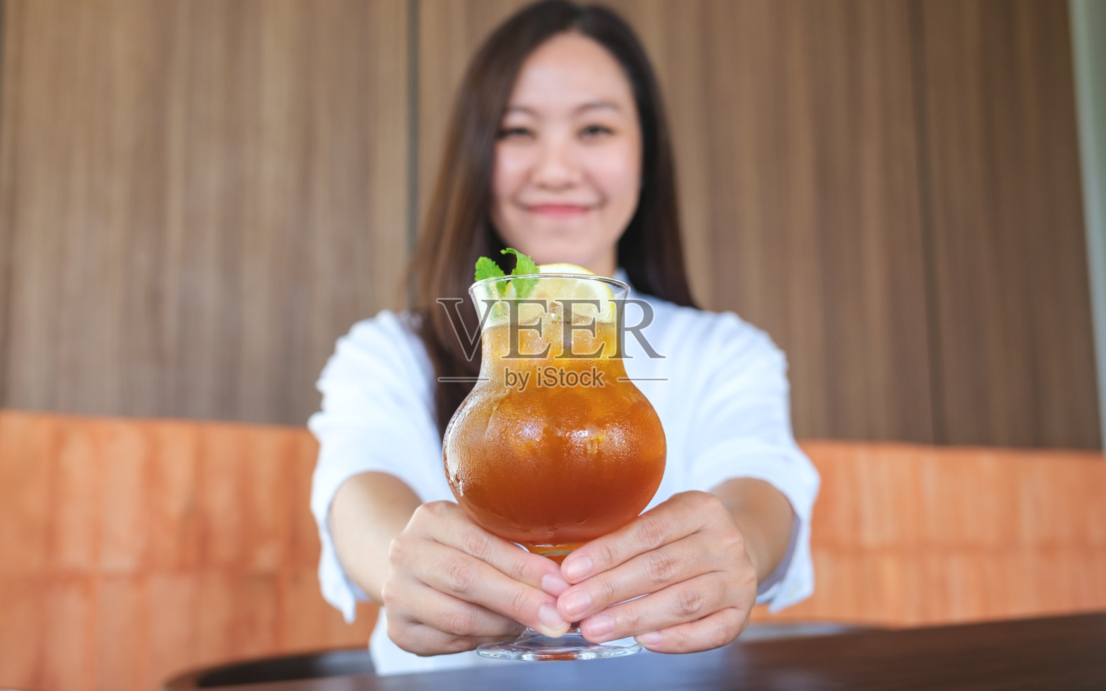 图为一名妇女端着一杯冰柠檬茶照片摄影图片