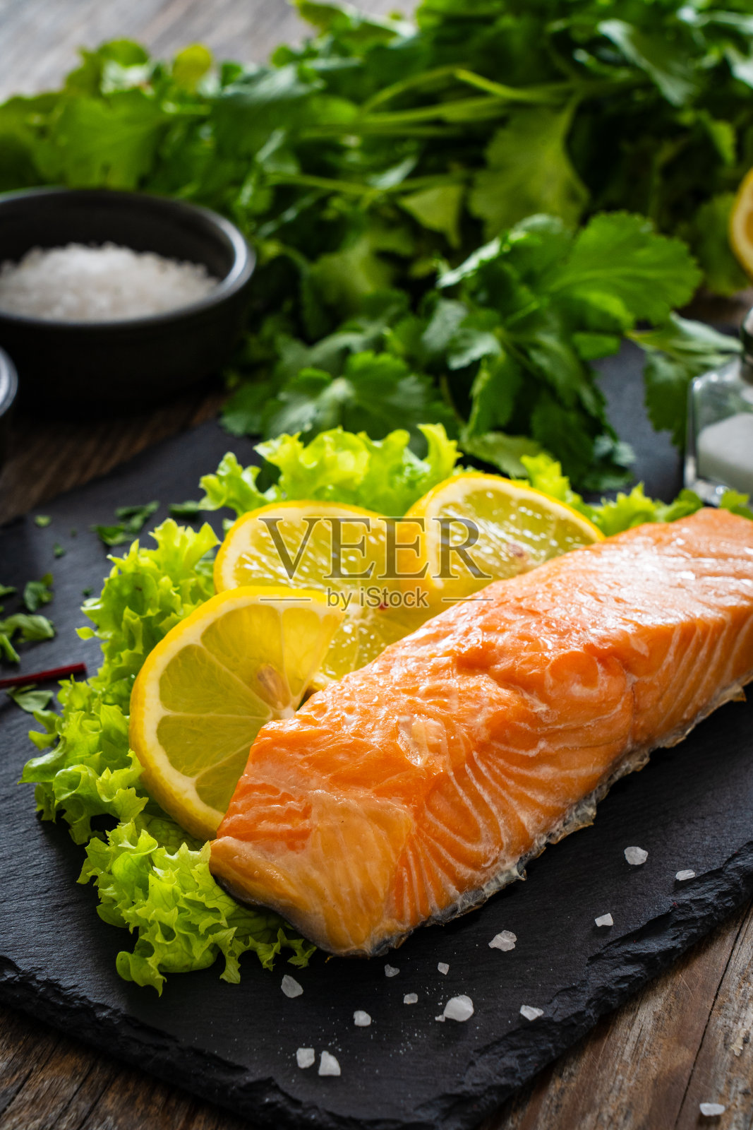 黑石盘子里的熏鲑鱼配柠檬和青菜放在木桌上照片摄影图片