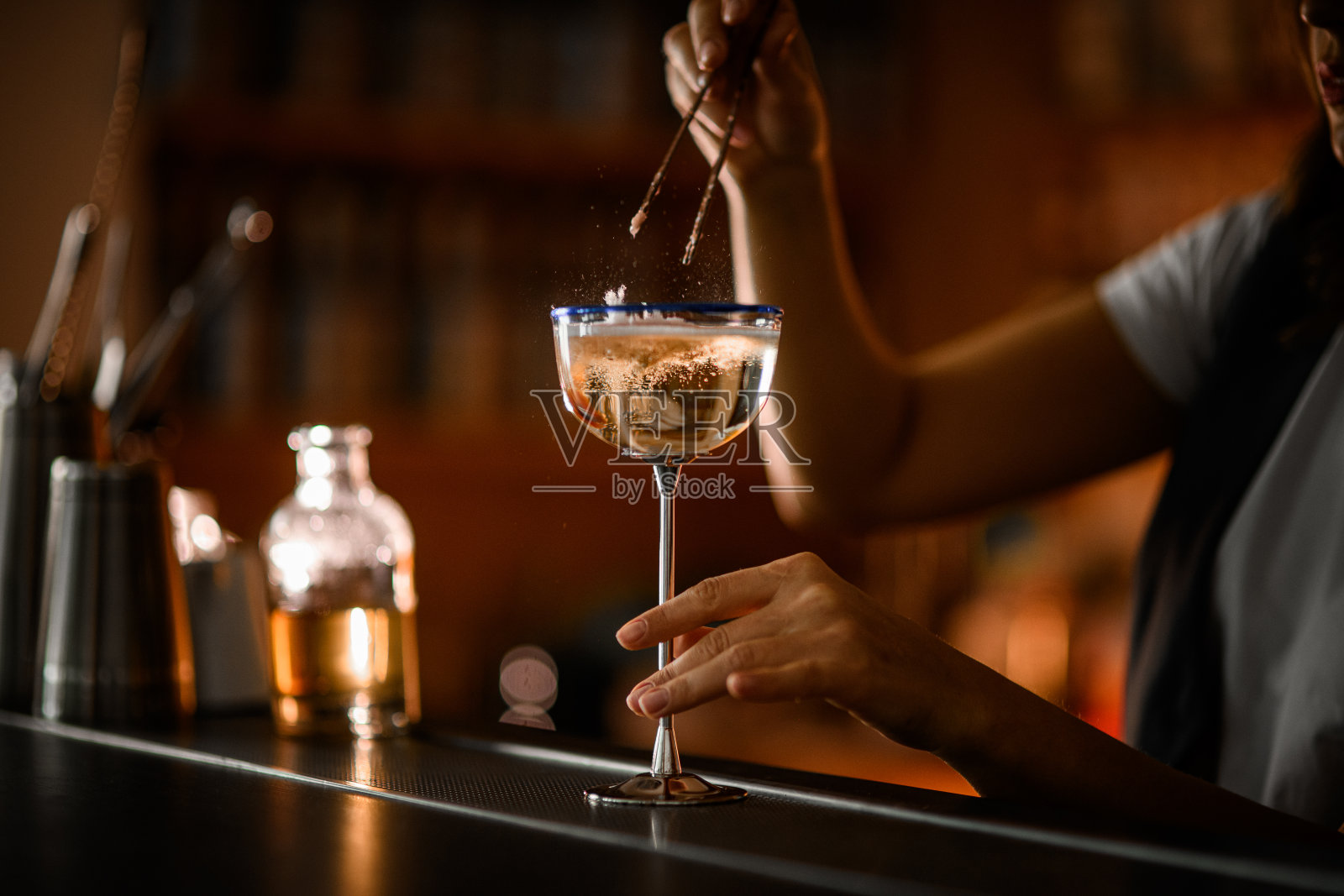 一个女酒保的手把一块棉花糖淹死在一个高高的金属腿上的玻璃杯里照片摄影图片