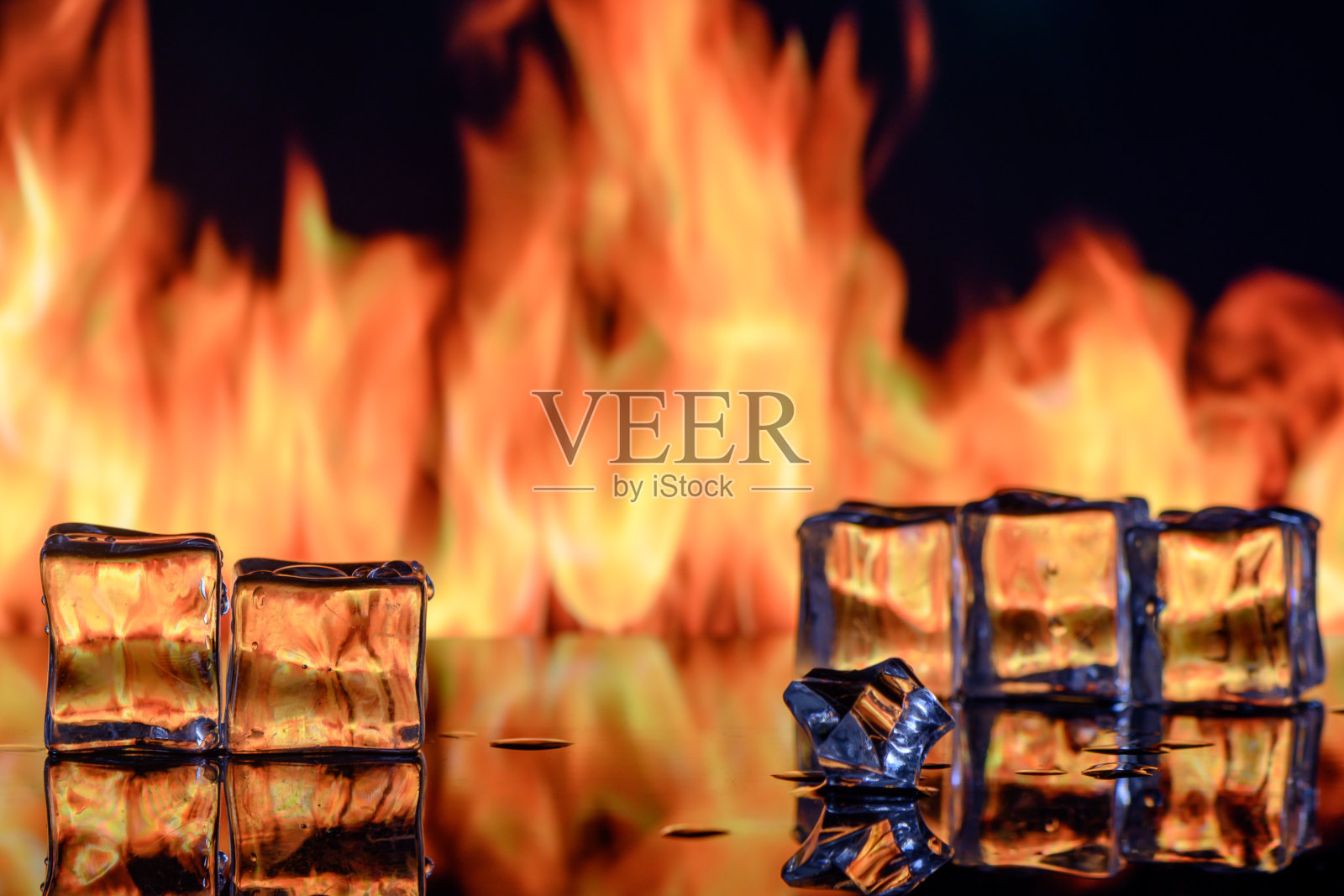 工作室拍摄的燃烧的冰晶和黑色反光背面的烟雾照片摄影图片