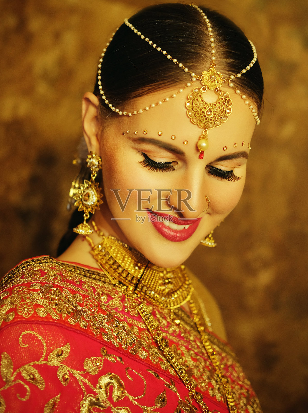 美丽的印度女孩在家里微笑的肖像。年轻的女模特戴着金色的首饰。照片摄影图片