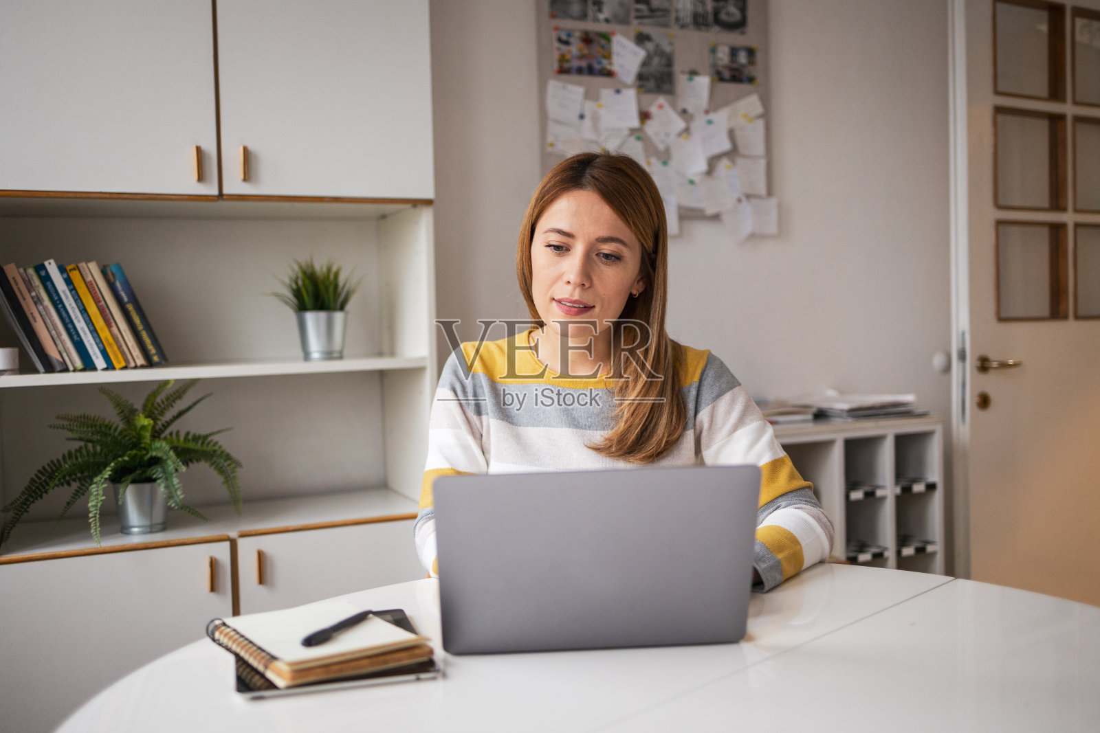 穿着便装的自信女性在家庭办公室使用笔记本电脑照片摄影图片