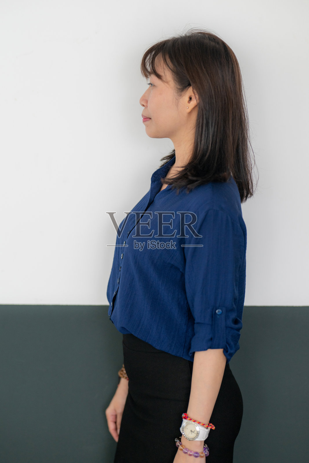 一位40多岁的女商人在办公室里若有所思地看着别处。穿着西装站在办公室里的职业女性。照片摄影图片