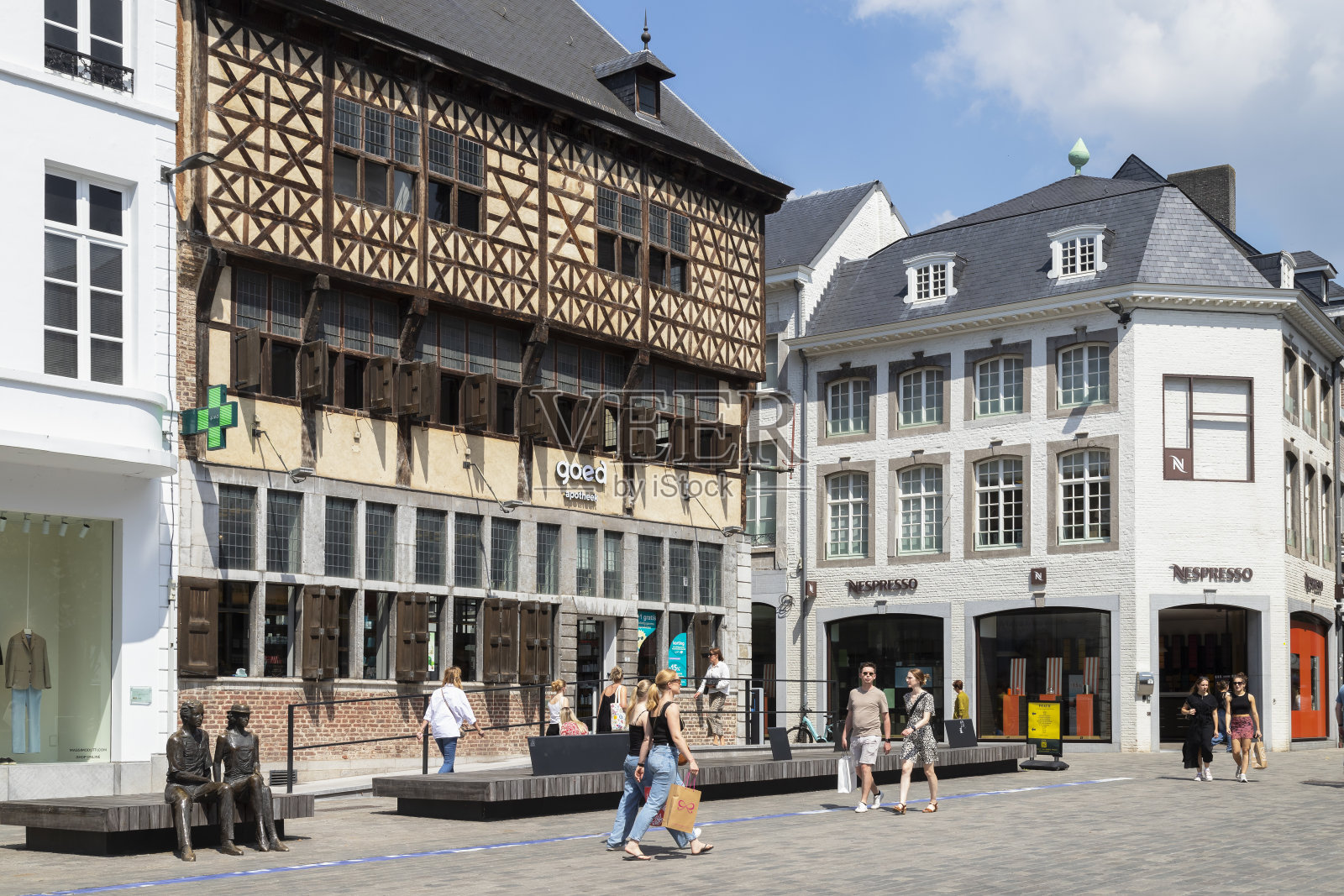 人们走过比利时哈瑟尔市中心广场上的半木结构房屋“t Sweert”。照片摄影图片