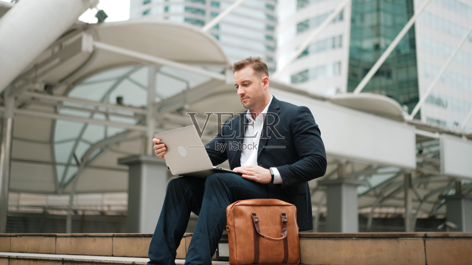 在楼梯上用笔记本电脑工作的专业商人的低角度视图。彬彬有礼的。照片摄影图片
