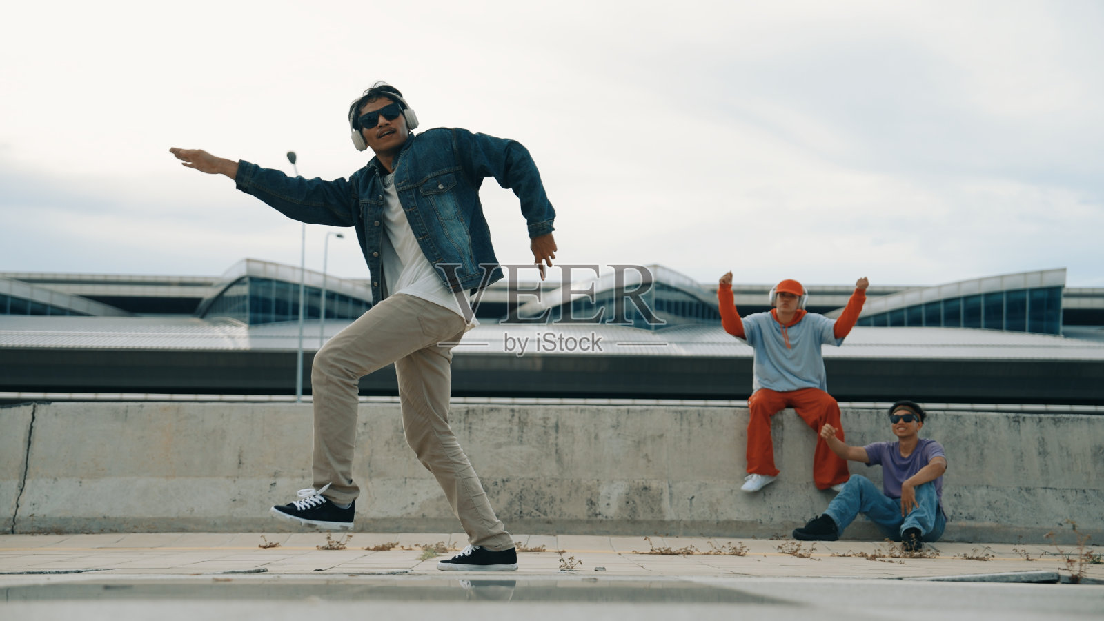 霹雳舞演员在朋友的欢呼声中尽情表演自由式动作。活泼的。照片摄影图片