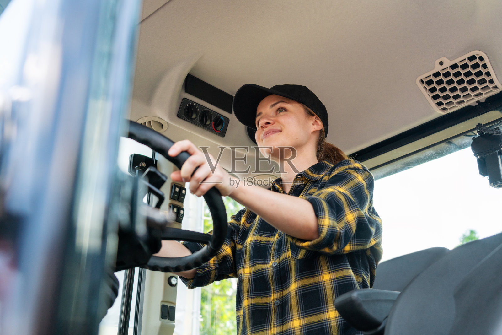 白人女牧场主操作农用拖拉机的低角度肖像。农业占领和劳动节。照片摄影图片