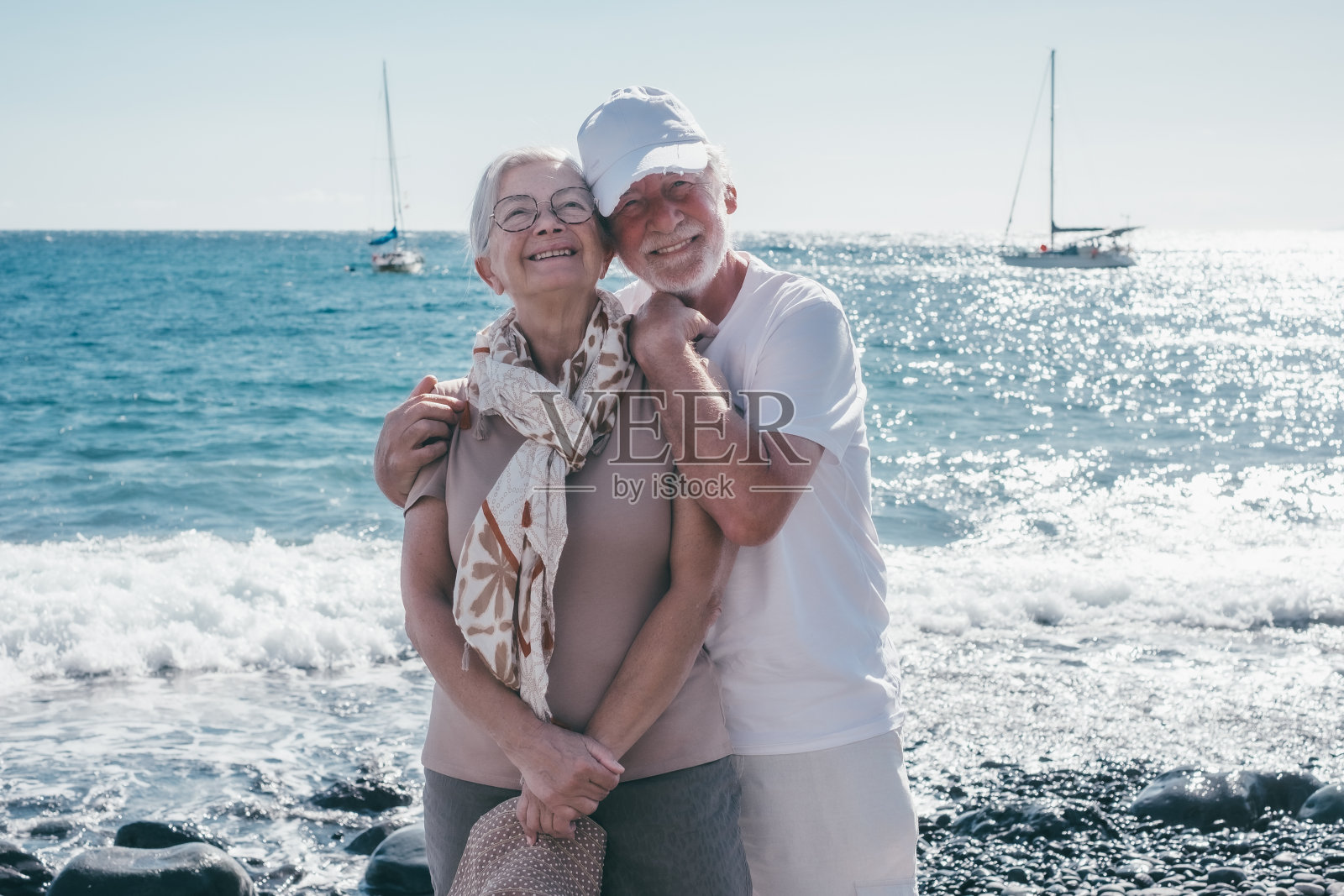 度假时微笑的老夫妇站在海边看着相机享受退休生活和自由的肖像，大海的地平线照片摄影图片