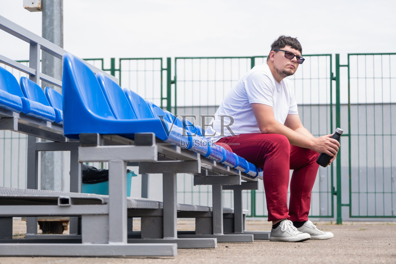 运动员拿着一瓶水坐在体育场的座位上休息照片摄影图片