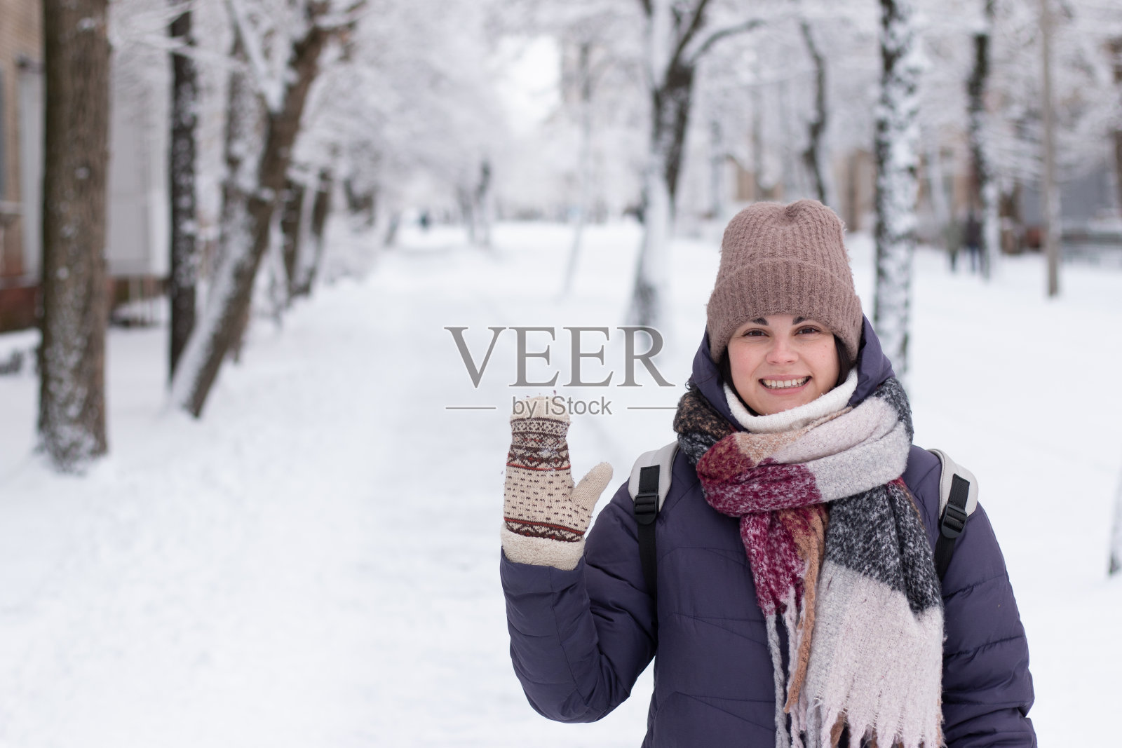 下雪的时候，年轻的美女戴着围巾在户外微笑照片摄影图片