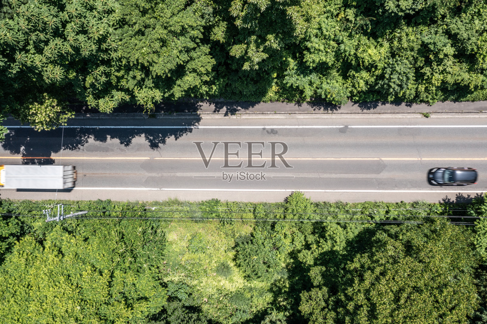 无人机摄影:一条被树木环绕的道路的俯视图，上面行驶着汽车照片摄影图片