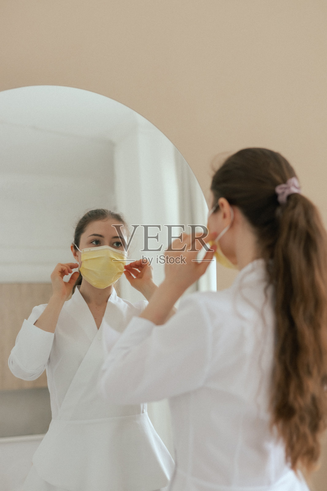 特写女全科医生医生穿着白色服装，在浅色背景上戴着口罩。医学和保健的概念。系列的一部分。照片摄影图片