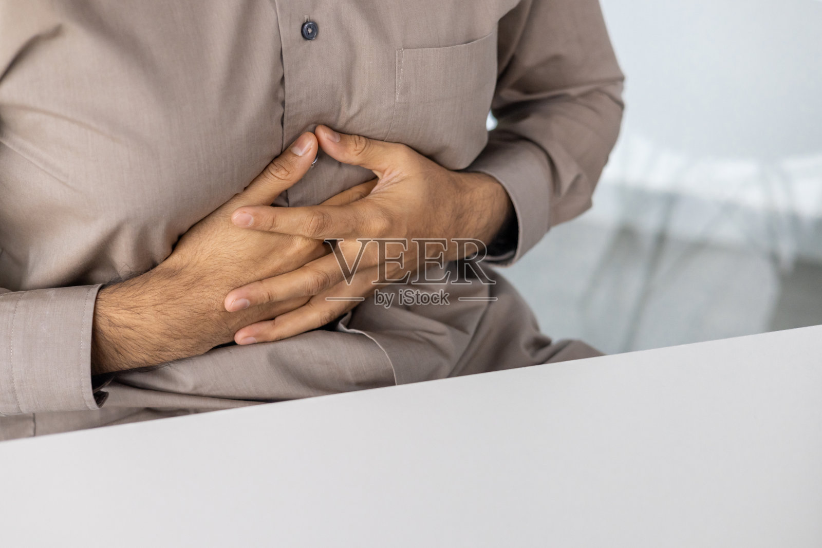 用双手捂着肚子，感到疼痛或不适的人照片摄影图片