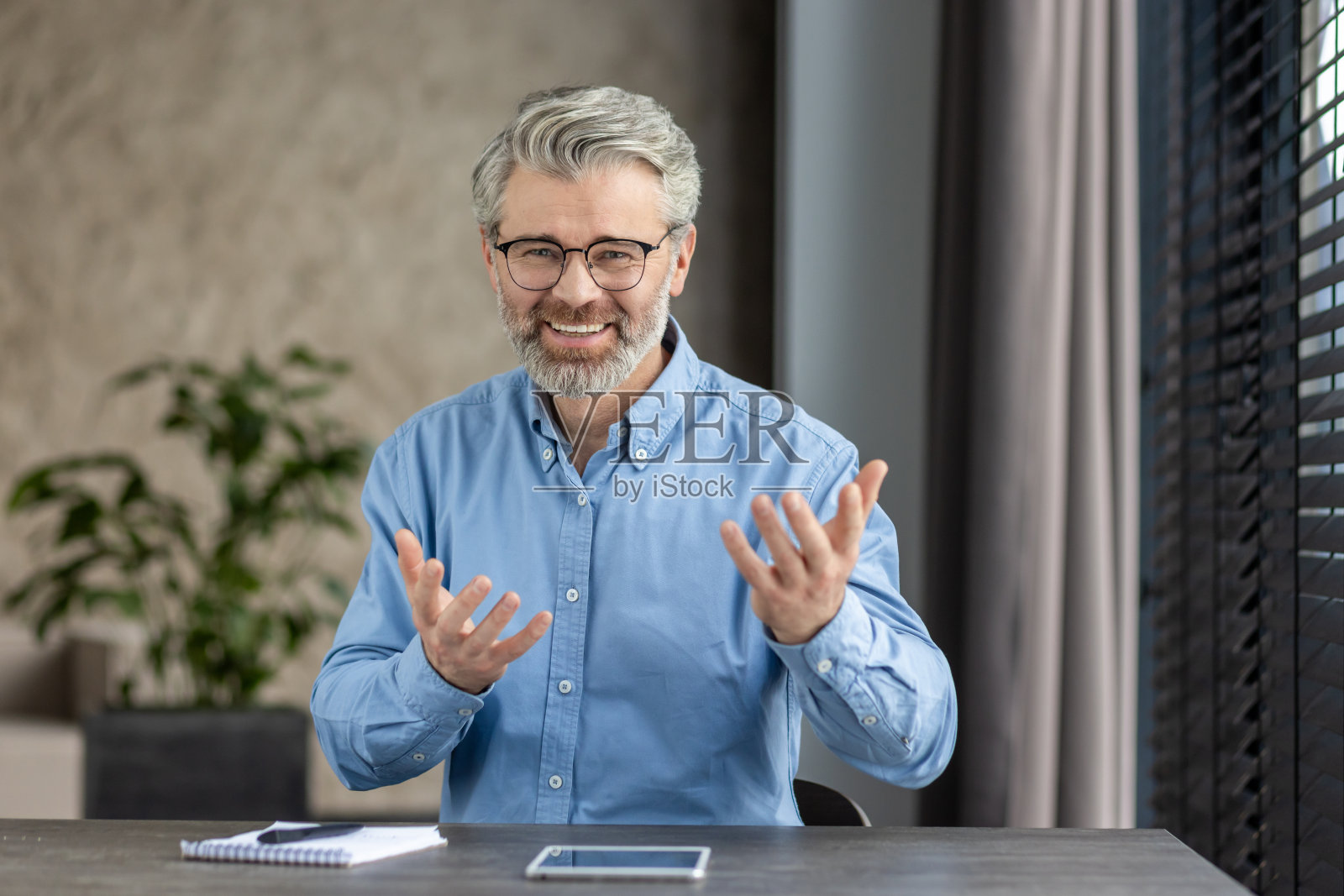 穿着休闲装的开朗的高级男子在现代家庭办公室里进行视频通话，面带微笑照片摄影图片