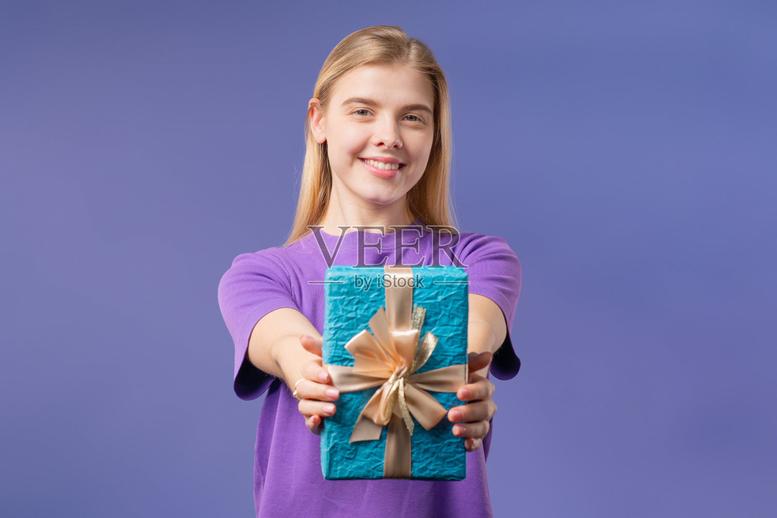 快乐少女礼盒紫罗兰背景。小姐微笑着，送给你照片摄影图片