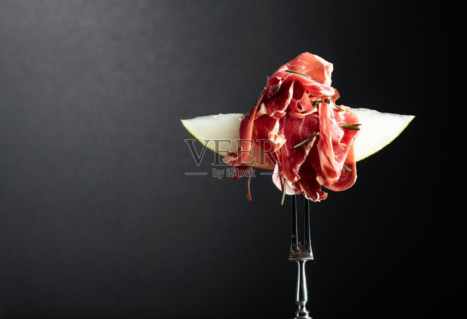 黑底熏火腿和迷迭香甜瓜。照片摄影图片