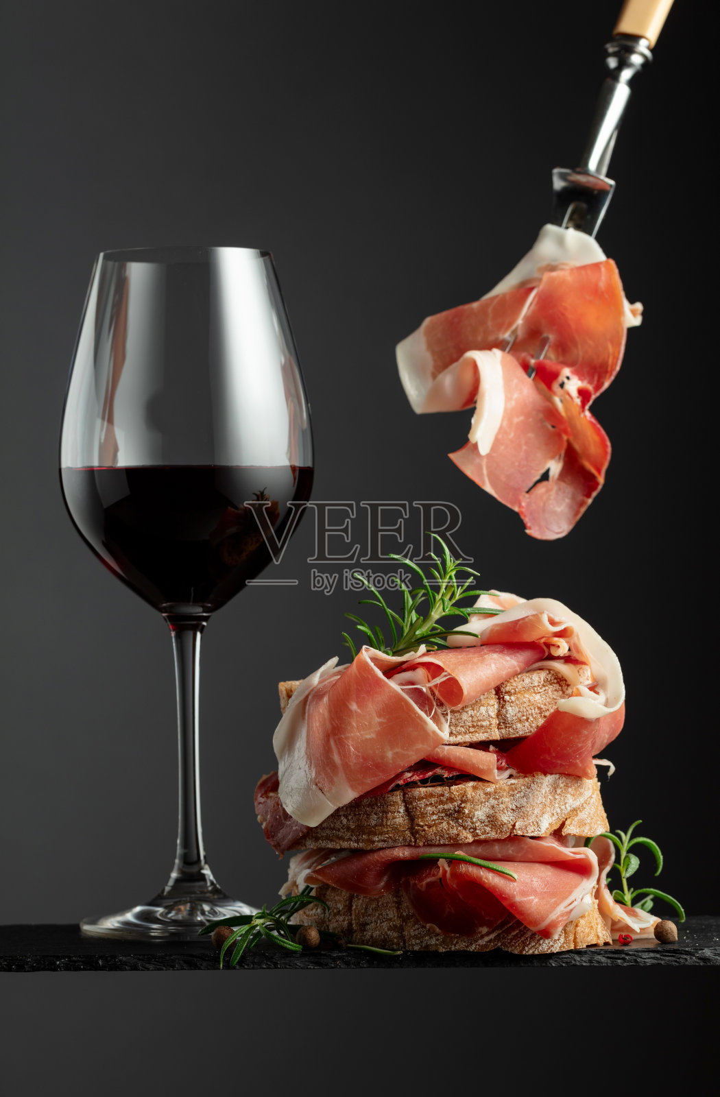 意大利火腿，迷迭香和一杯红酒。照片摄影图片