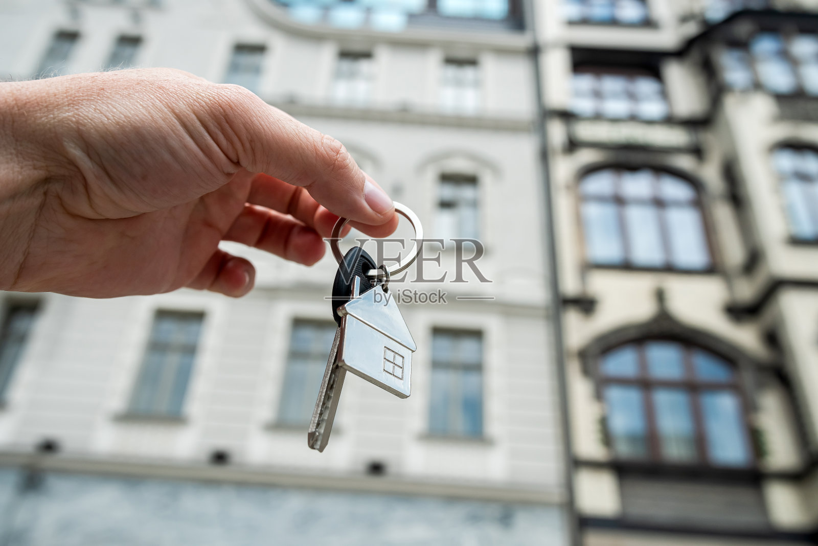 特写房地产经纪人拿着钥匙，房子对着新的现代化建筑照片摄影图片