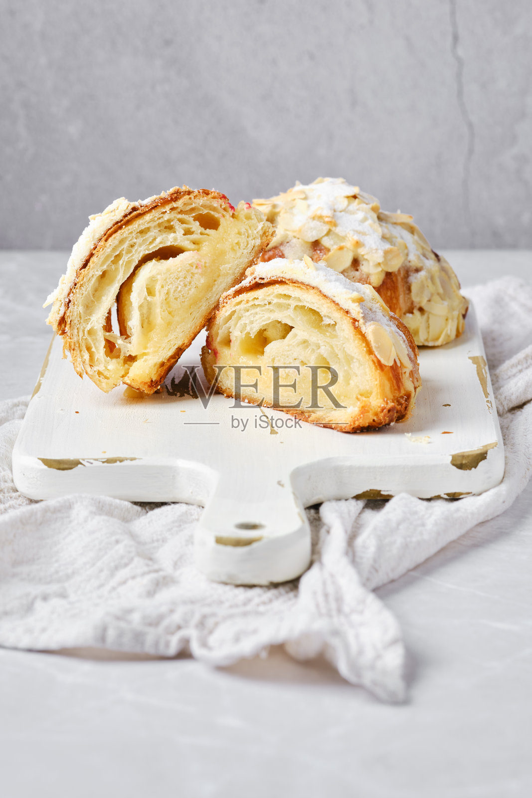 在明亮的背景下，将焦糖和花生屑切成两半的牛角面包的横截面照片摄影图片