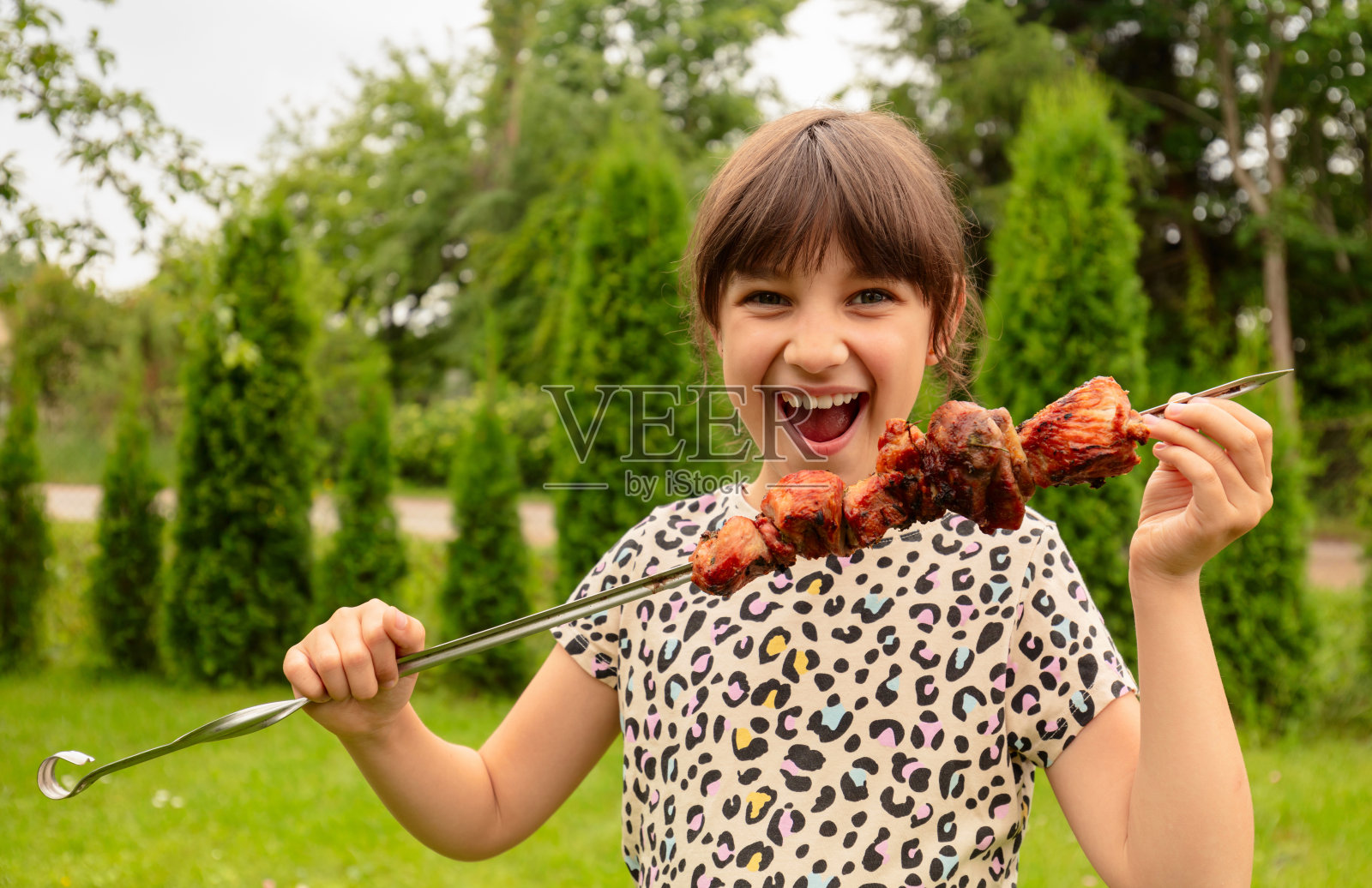 吃羊肉串的小女孩。照片摄影图片