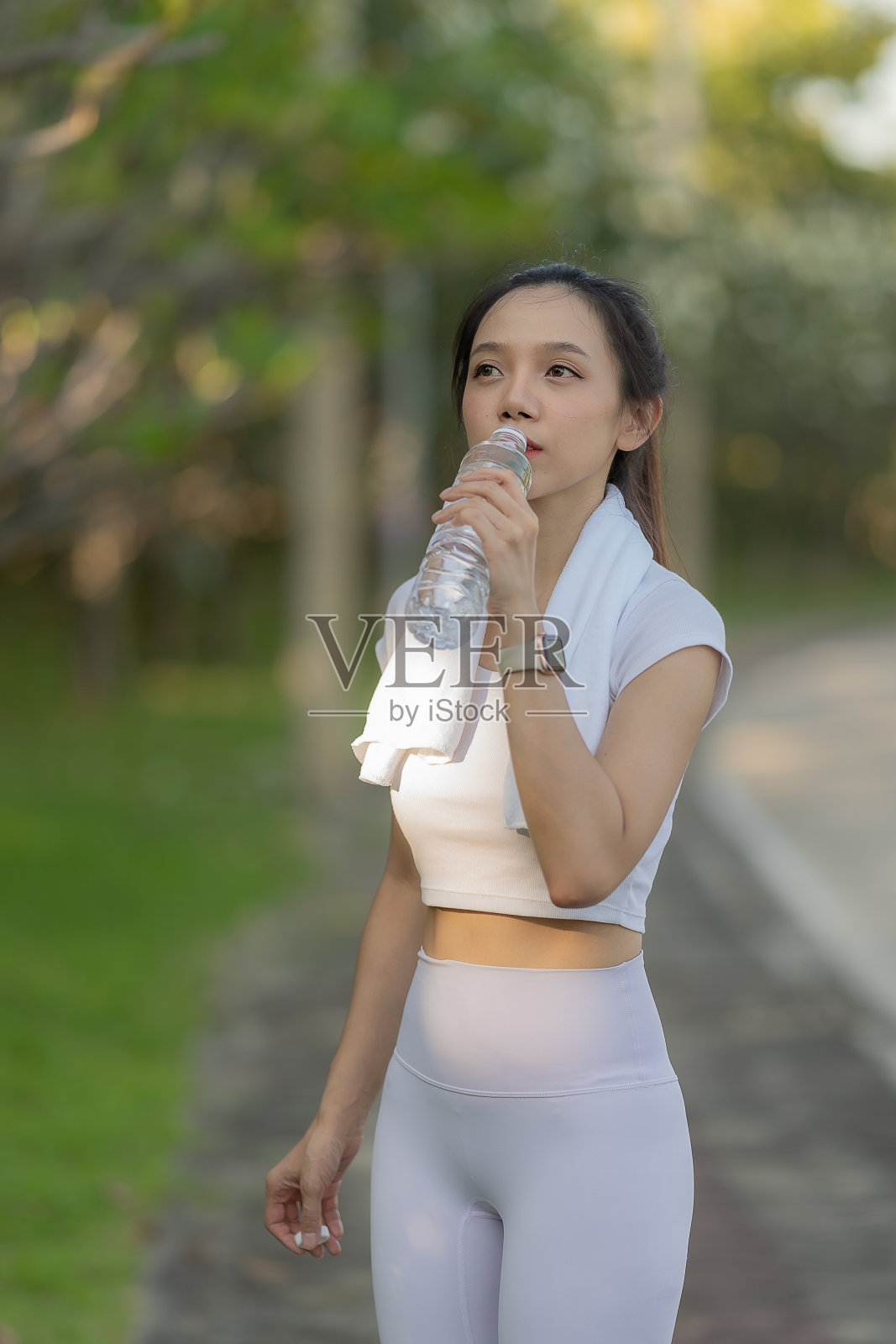 亚洲女性用健康运动饮料解渴运动前喝瓶装矿泉水。垂直的图像。照片摄影图片