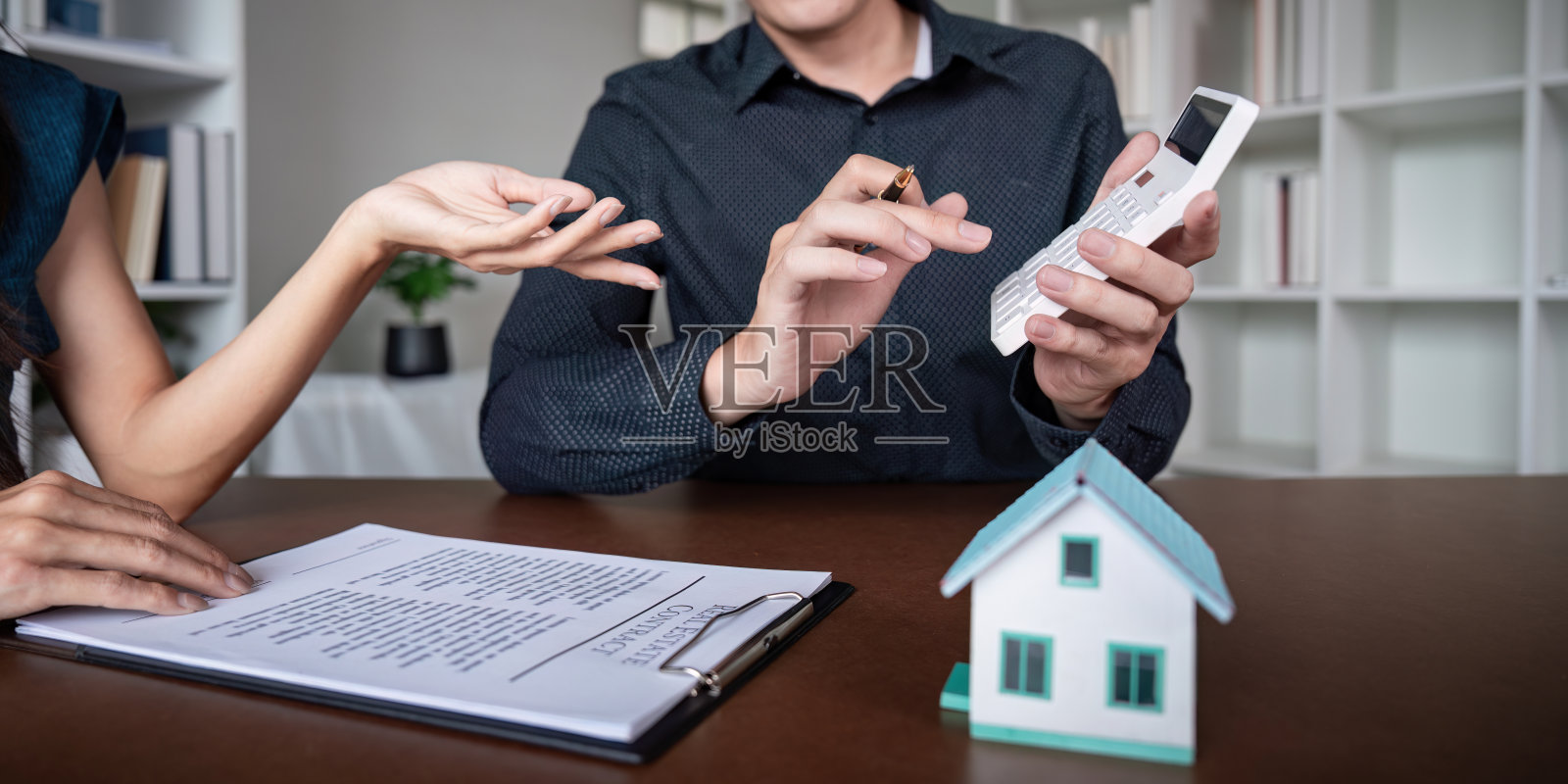 房地产经纪人与客户洽谈购房合同、签署协议并计算抵押贷款照片摄影图片