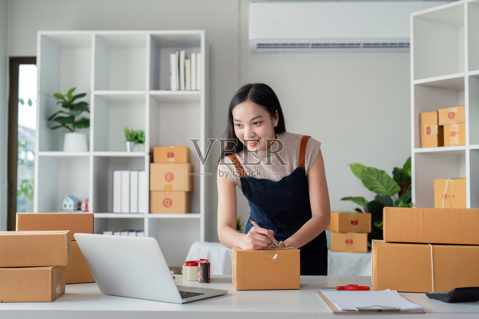 年轻的企业家在现代家庭办公环境中为在线电子商务业务准备包裹箱照片摄影图片