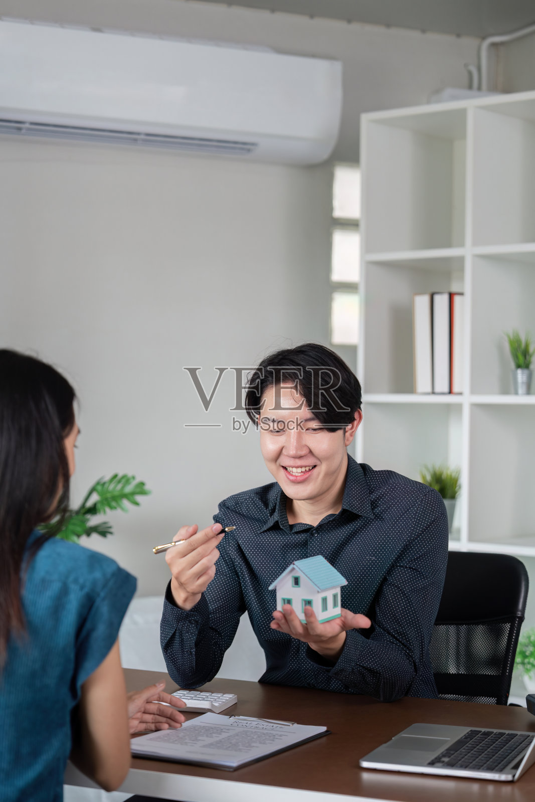 房产中介在现代办公场所与客户签订房产买卖文件照片摄影图片